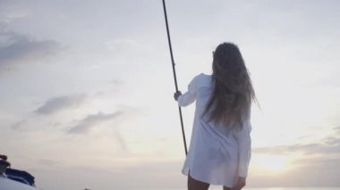 Seksi kız gün batımında Tayland 'da adanın yakınında yelken açan bir yatta dans ediyor.