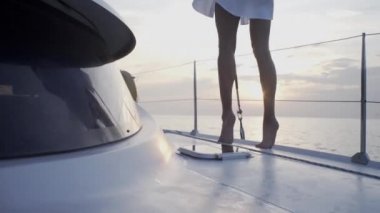 Seksi kız gün batımında Tayland 'da adanın yakınında yelken açan bir yatta dans ediyor.