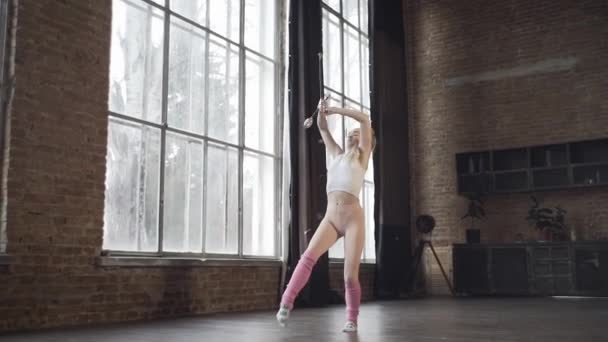 Dívka v podkroví studia ukazuje cvičení s rytmickou gymnastikou