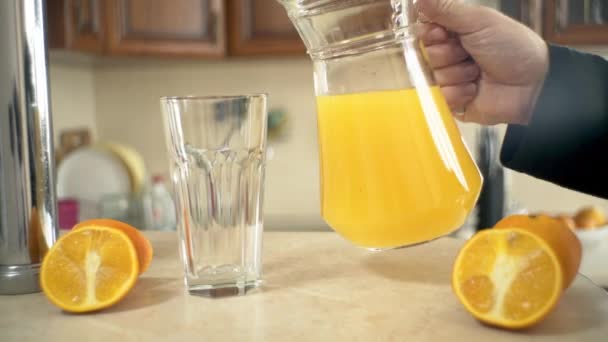 新鲜的榨橙汁 新鲜的橙汁从酒瓶倒入厨房的杯子 准备好橙汁和新鲜的橙汁 — 图库视频影像