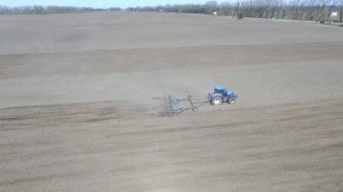 Traktör tarlayı geçiyor, tohum ekmek için toprağı sürüyor, baharda tahıl ekmeye hazırlanıyor.