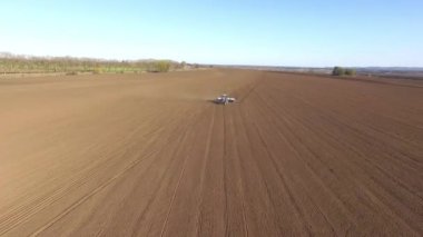 Traktör tarlayı geçiyor, tohum ekmek için toprağı sürüyor, baharda tahıl ekmeye hazırlanıyor.