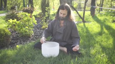 Bir qigong ustası gong ve kristal kase kullanarak meditasyon yapar, Kristal Tibet şarkı kasesi, bir usta vücut için enerji alır.