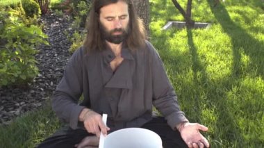 Bir qigong ustası gong ve kristal kase kullanarak meditasyon yapar, Kristal Tibet şarkı kasesi, bir usta vücut için enerji alır.
