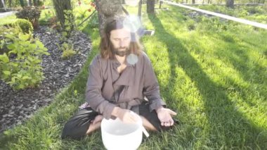Bir qigong ustası gong ve kristal kase kullanarak meditasyon yapar, Kristal Tibet şarkı kasesi, bir usta vücut için enerji alır.