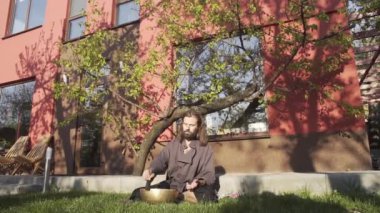 Bir qigong ustası gong ve kristal kase kullanarak meditasyon yapar, Kristal Tibet şarkı kasesi, bir usta vücut için enerji alır.