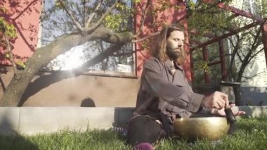 Bir qigong ustası gong ve kristal kase kullanarak meditasyon yapar, Kristal Tibet şarkı kasesi, bir usta vücut için enerji alır.