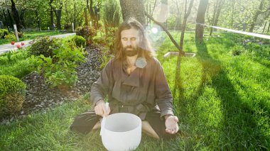 Bir qigong ustası gong ve kristal kase kullanarak meditasyon yapar, Kristal Tibet şarkı kasesi, bir usta vücut için enerji alır.