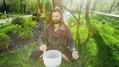 Bir qigong ustası gong ve kristal kase kullanarak meditasyon yapar, Kristal Tibet şarkı kasesi, bir usta vücut için enerji alır.
