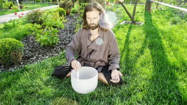 Bir qigong ustası gong ve kristal kase kullanarak meditasyon yapar, Kristal Tibet şarkı kasesi, bir usta vücut için enerji alır.