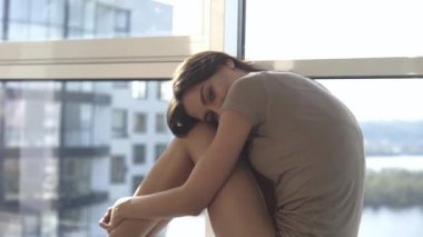Günbatımında seksi bir manken panoramik pencerelerle evinde poz veriyor. Duygu dolu akşam havası sakin, şehir ve Dinyeper nehri dışında..