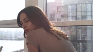 Günbatımında seksi bir manken panoramik pencerelerle evinde poz veriyor. Duygu dolu akşam havası sakin, şehir ve Dinyeper nehri dışında..