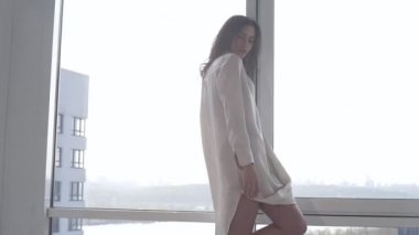 Günbatımında seksi bir manken panoramik pencerelerle evinde poz veriyor. Duygu dolu akşam havası sakin, şehir ve Dinyeper nehri dışında..