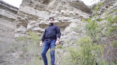 Adam kanyon boyunca yürüyor, etrafı kayalarla çevrili, nehrin kenarına bakıyor, arkadaşlarına bakıyor ve onları arıyor.