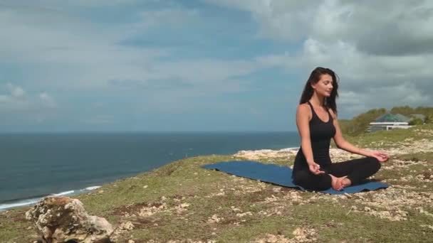 Piękna kobieta w czarny medytuje na skraju klifu — Wideo stockowe