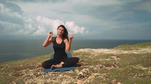 Fekete haj rögzítő és szélén szikla meditál a gyönyörű nő — Stock videók