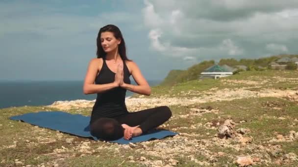 Mooie vrouw in zwarte mediteren op de rand van de klif — Stockvideo