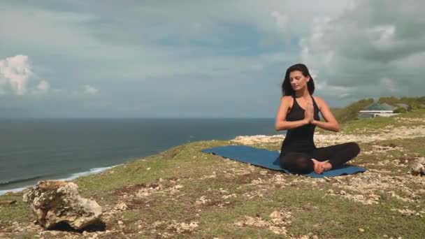 Belle femme en noir méditant sur le bord de la falaise — Video