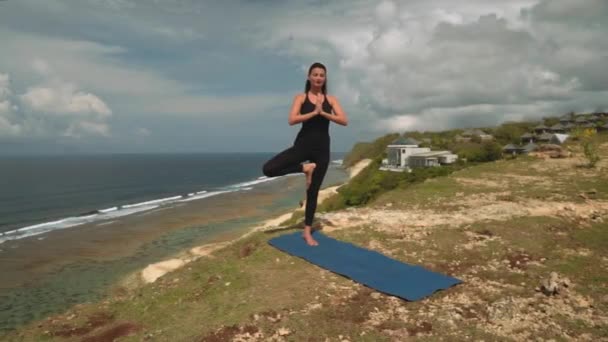 Kobieta w drzewo jogi pozować na skraju klifu — Wideo stockowe