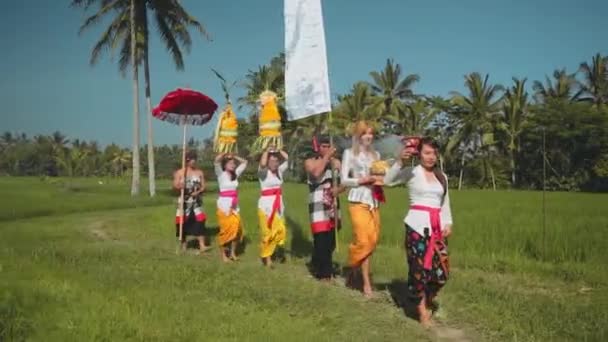 Procesión balinesa recorriendo arrozales con ofrendas — Vídeo de stock
