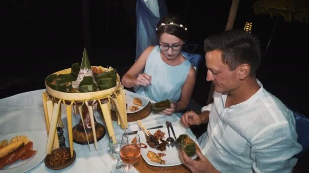 Kaukasische paar proeven van traditionele balinese schotel Rijsttafel plaat tijdens het diner — Stockvideo