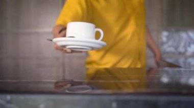 Masada garson tarafından sarı gömlek yerleştirilmiş beyaz kahve Kupası kapatın