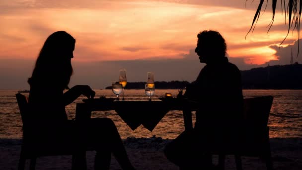 Silhouettes de couple dînant sur la plage au coucher du soleil — Video