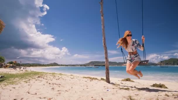 Девушка качается туда-сюда на веревке качели на пляже в Ломбоке — стоковое видео