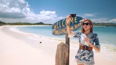Selfie Tanjung Aan yakınındaki beyaz kum plaj işareti Lombok, Endonezya alarak kız