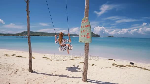 女の子のロンボク島のビーチのロープ スイングに前後スイングします。 — ストック動画