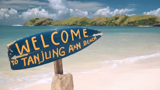 Placa de surf azul Bem-vindo à praia Tanjung Aan em Lombok, Indonésia — Vídeo de Stock