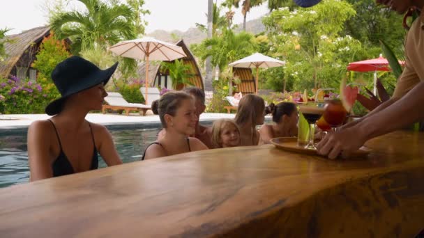 Гости, принимающие напитки в баре у бассейна — стоковое видео