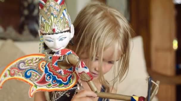 Маленька дівчинка оглядає балінезійську ляльку — стокове відео