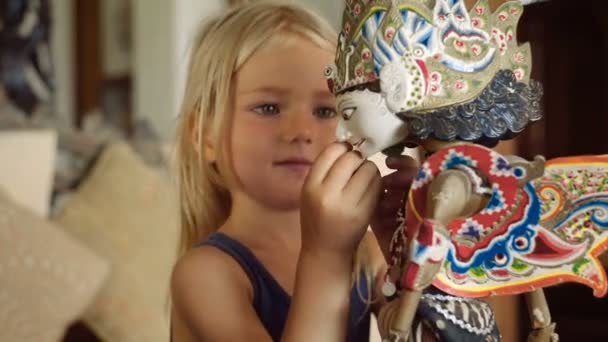 Маленька дівчинка оглядає балінезійську ляльку — стокове відео