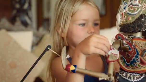 Kleines Mädchen lächelt und umarmt eine balinesische Puppe — Stockvideo