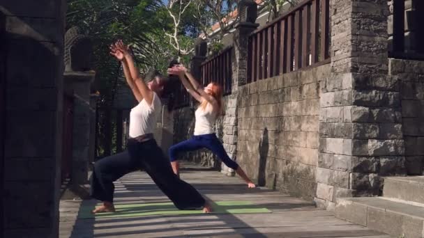 Two women doing warrior yoga pose on balcony — Stock Video