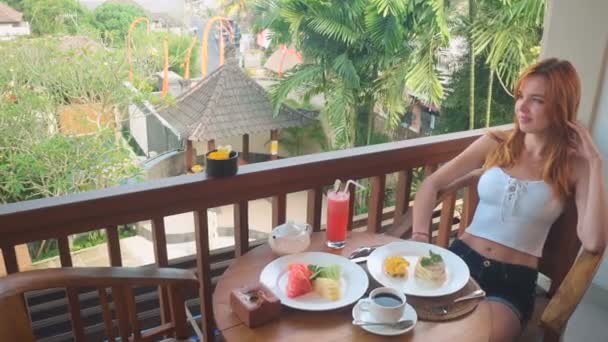 Молодая женщина завтракает на балконе в Убуде — стоковое видео