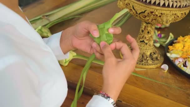 Закрыть женщину, делающую украшения из пальмовых листьев — стоковое видео