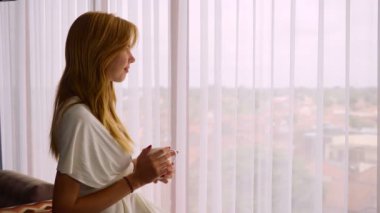 Kupası ayakta pencere yanında kadınla