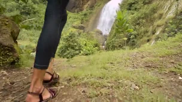 Young woman walking towards waterfall — Stock Video