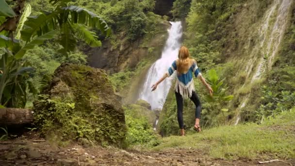 Junge Frau hebt Hände am Wasserfall — Stockvideo