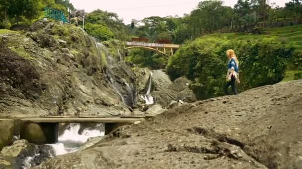 Jonge vrouw lopen over stream in Baturraden — Stockvideo