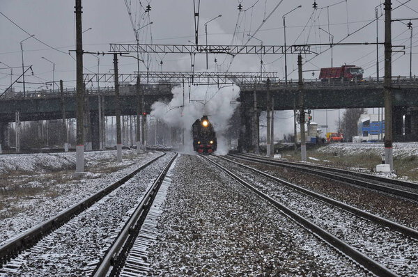 An old smoking locomotive running on rails.