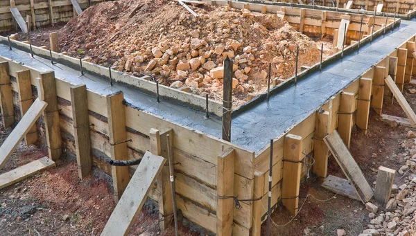 Construction of a low-rise building. Pouring concrete into a deepened strip Foundation with a high plinth.