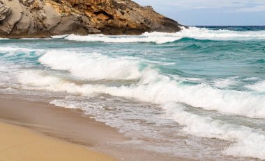 Kum kıyısında kayalar ve dalgalar