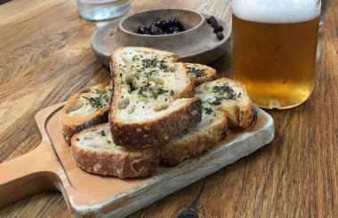 Sebzeli kabuklu ekmek, zeytin ve bir bardak bira.