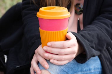Female hand holding reusable coffee mug. Take your coffee to-go.