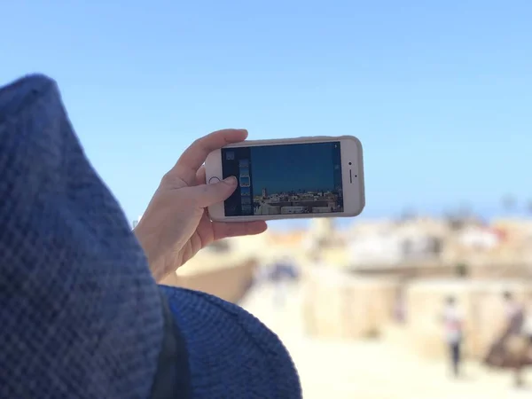 Female hand holding mobile phone with image of El Jadida ,Morocco