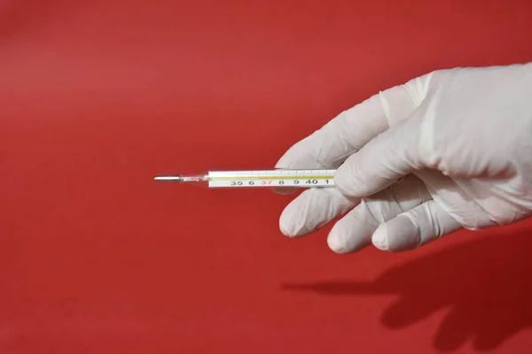 Hand in white medical glove holds medical mercury thermometer — Stock Photo, Image