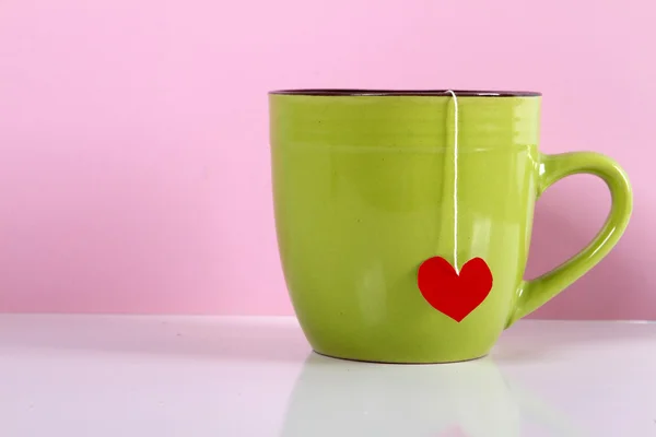 Caneca saco de chá coração em um fundo rosa . — Fotografia de Stock